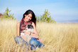 smiling young woman hugging her small havanese dog on a meadow with autumn dry grass 